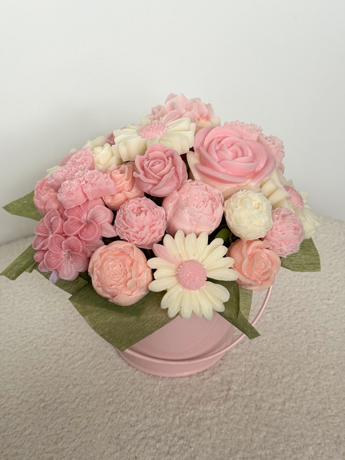 Pink and white flower arrangement on a pink stand against a light background