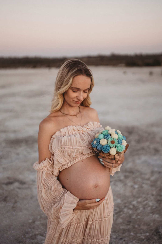 Pregnant woman holding a bouquet of flowers in a natural setting
