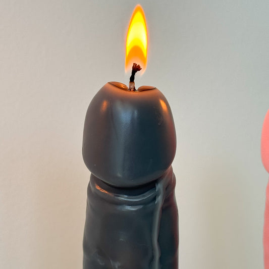 A dark gray novelty candle with a sculpted, elongated shape and a lit flame, shown against a plain light gray background.